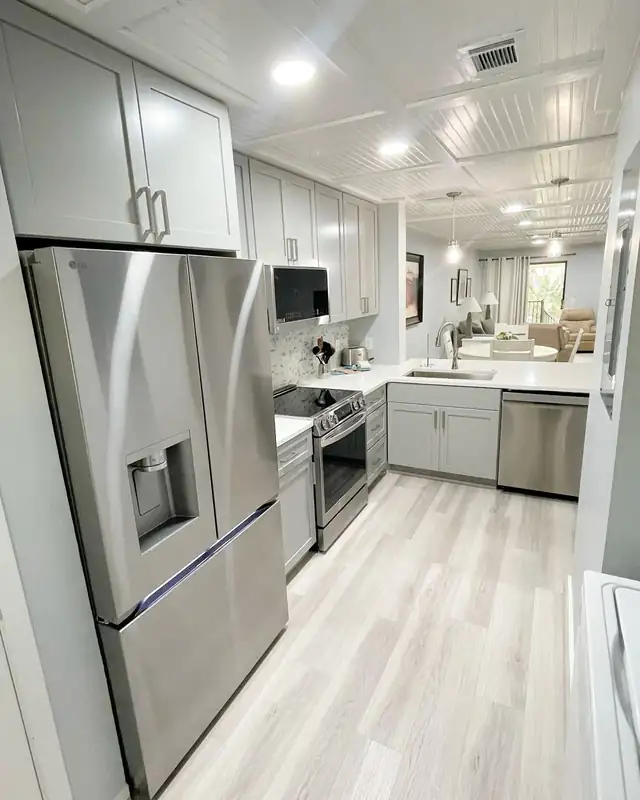 Galley kitchen with light wood-look plank flooring, stainless steel appliances and light gray cabinets