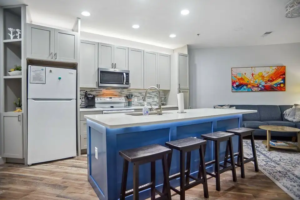 Kitchen remodeling on Hilton Head Island: light gray shaker cabinets, white counters and a blue island with four bar stools